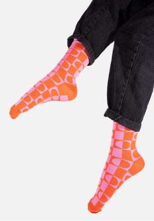 Pomarańczowe i różowe skarpetki z geometrycznym wzorem składającym się z kwadratów i owalów. Wykonane z gładkiego, elastycznego materiału, idealne do noszenia na co dzień.