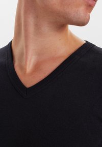 Black cotton V-neck t-shirt with a smooth texture, featuring a ribbed neckline and a fitted design, showcased from the side.