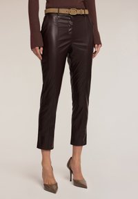 Bordeaux neplederen broek met een rechte pasvorm, hoge taille en riem. Gladde textuur, zijnaadstiksel en cropped lengte. Gepaarde met puntige hakken.