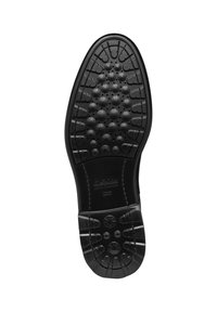 Suela de goma negra con patrón texturizado, que presenta grips en forma circular y de estrella. Incluye la marca estampada en el centro.