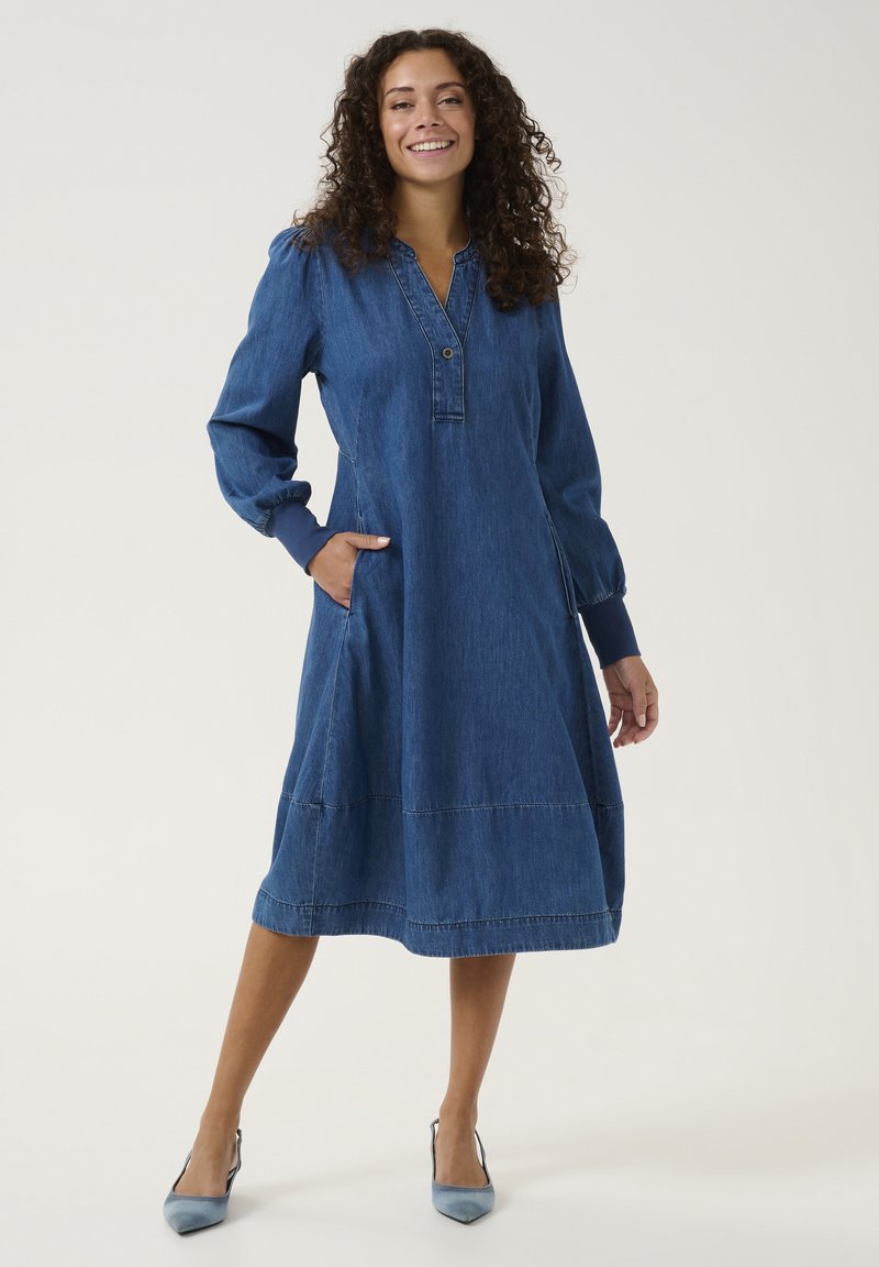 Jeansklänning med långa puffärmar, knäppt krage, sidofickor, medellång, i en enhetlig blå färg med sömmar detaljer.
