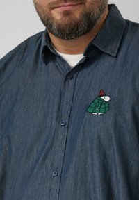 Donker denim overhemd met knopen, met een geborduurd ontwerp van een groene en witte schildpad op de borst, blauwe knopen en een zachte textuur.