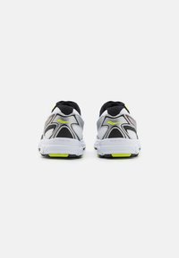 Sneaker sportive grigie e nere con tomaia in rete, caratterizzate da accenti giallo fluorescente e pannelli testurizzati, progettate per comfort e supporto.
