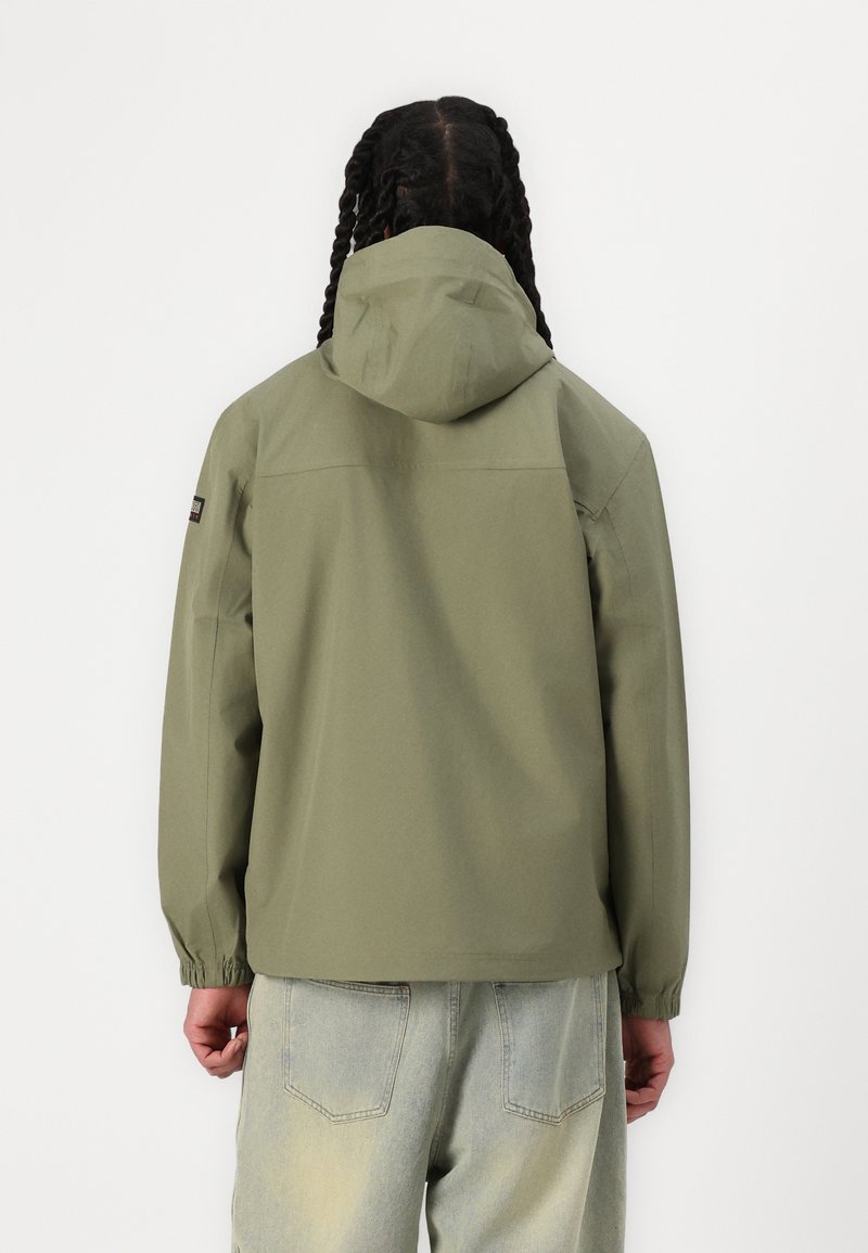 Chaqueta con capucha de color verde oliva claro, con puños elásticos y un corte relajado. El material parece suave, diseñado para uso casual.