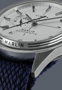 Orologio Timex Marlin Automatic con cassa in acciaio inox lucidato argento, quadrante bianco, cinturino in tela intrecciata blu e indicatori delle ore prominenti.