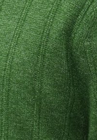 Zielona dzianinowa tkanina o fakturowanym, prążkowanym wzorze. Materiał wydaje się miękki i lekko elastyczny, ukazując różne odcienie zieleni.