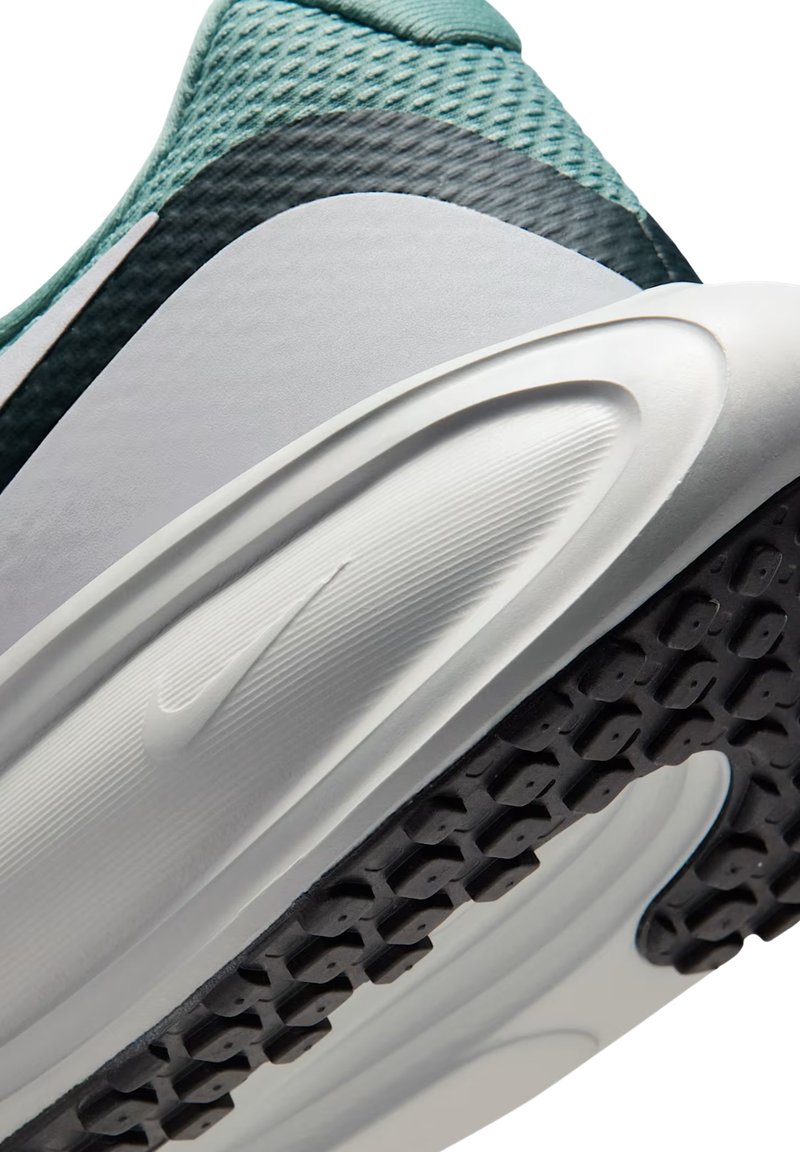 Un gros plan d'une chaussure de sport avec une tige en maille vert menthe, une semelle intermédiaire blanche avec des stries et une semelle extérieure en caoutchouc noir avec des motifs de traction.