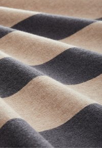 Randig tyg i beige och mörkgrått, med ett vågigt mönster. Mjuk textur med en slät yta och väldefinierad färgkontrast.