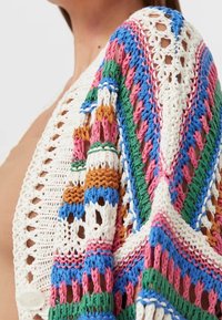 Strickjacke mit einem geometrischen Muster in leuchtenden Farben: Blau, Pink, Grün, Orange und Weiß. Offene Maschen mit Knopfdetails.