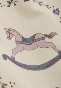 Illustratie van een schommelpaard in het roze met een blauwe zadel, voorzien van een bruine manen, op een crèmekleurige achtergrond met bloemenpatronen en decoratieve accenten.