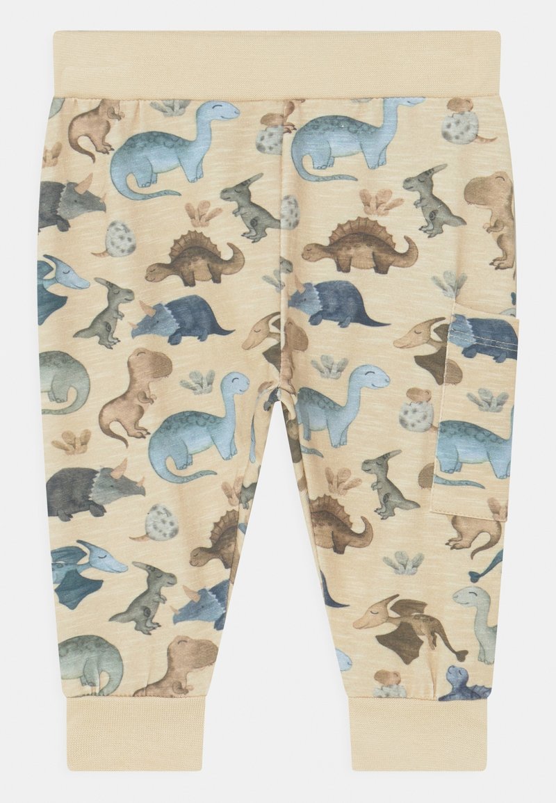 Pantalon beige pour enfants avec taille et poignets élastiques, motifs de dinosaures bleus et marron, et une poche latérale sur la jambe droite.