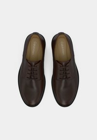 Καφέ δερμάτινα παπούτσια με λείο φινίρισμα, με σχεδιασμό με κορδόνια και στρογγυλεμένη μύτη. Διακριτική επωνυμία στο εσωτερικό πέλμα.