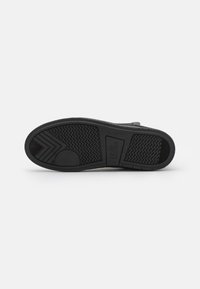 Talpa de sneakers din cauciuc negru, cu un model texturat, având un toc rotund și branding pe lateral. Margini netede, fără uzură vizibilă.