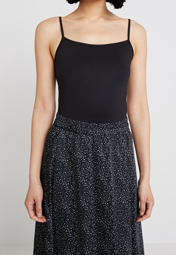 Černý těsný body s tenkými ramínky, doplněný vysokým černým sukní s bílým tečkovaným vzorem. Hladká tkanina, přiléhavý střih.