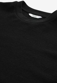 Sweatshirt nero a costine con scollatura rotonda, caratterizzato da una texture morbida e un'etichetta che recita "NEXT" all'interno del colletto.