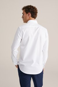Witte langemouwenhemd met een button-down kraag, een gladde textuur en een afgeronde zoom. Gecombineerd met donkerblauwe broek, met een getailleerde pasvorm.