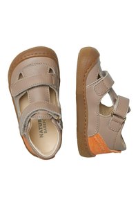 Bruna läderskor med en flexibel sula, som har två justerbara velcroremmar, cirkulära urtag och orangea mockadetaljer på sidorna.