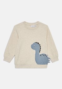 Beige barntröja med en blå dinosaurie-grafik och svarta detaljer. Tillverkad av mjukt tyg med långa ärmar och rundad halsringning.