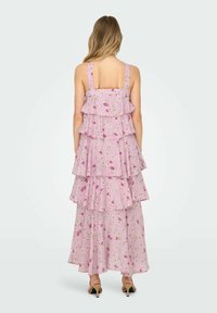 Rózsaszín virágmintás maxi ruha réteges fodrokkal, állítható pántokkal és lágy esésű szoknyával. Puha, könnyű anyagból készült, finom mintával.