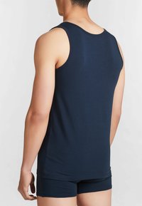 Top senza maniche blu navy realizzato in un tessuto liscio, con scollatura rotonda e vestibilità comoda, indossato con pantaloni corti scuri coordinati.