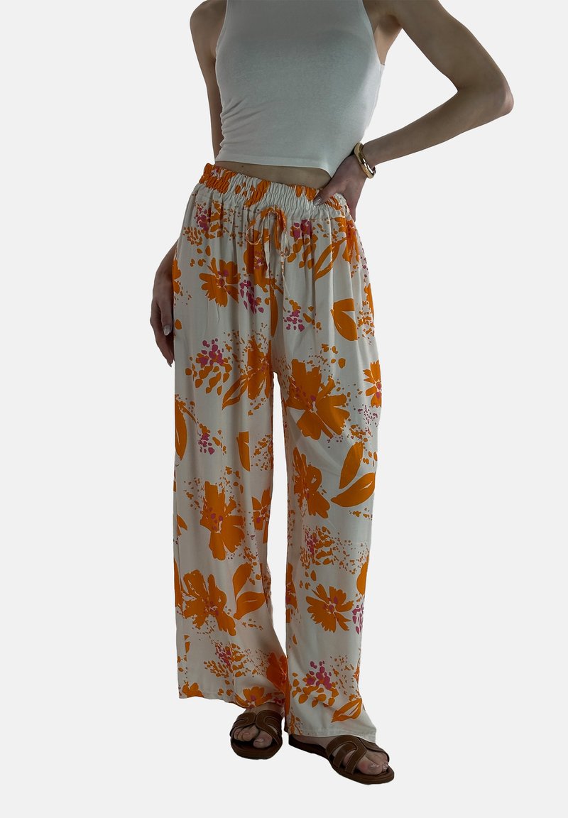 Lichte, loszittende broeken van een crèmekleurige stof versierd met grote oranje en roze bloemmotieven. Voorzien van een elastische tailleband met een trekkoord.