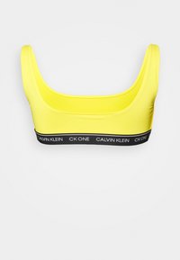 Top desportivo amarelo com decote redondo e alças largas. Apresenta uma faixa preta com o texto "CALVIN KLEIN CK ONE", textura suave.