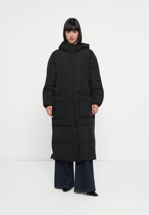 Manteau long noir rembourré avec capuche, deux poches avant et design matelassé. Dispose d'une fermeture éclair et de manches larges.