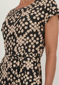 Zwarte jurk met een ronde halslijn, korte mouwen en een overal bieze bloemenpatroon. Bevat een tailleband en een vloeiende silhouet.