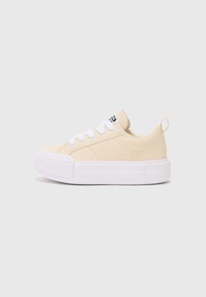 Canvas sneakers i lyse beige med hvite snørebånd, rund tå og hevet hvit såle; har en hælflik for enklere påkledning.