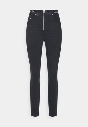 Zwarte high-rise skinny jeans met een ritssluiting aan de voorkant, voorzakken en een merkband met de tekst "CALVIN KLEIN".
