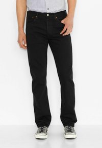 Zwarte rechte jeans met vijf zakken, zichtbare stiksels en een knoopsluiting. Draag ze met grijze sneakers en een lichtblauw shirt.