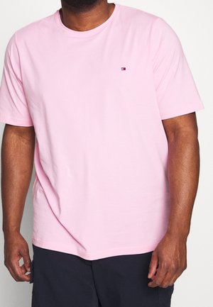 T-shirt en coton rose avec des manches courtes, un col rond et un petit logo sur la poitrine gauche. Le tissu a une texture lisse.