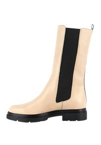 Botas de tobillo de cuero beige con un caña alta, que presentan paneles laterales elásticos negros, un acabado texturizado y una suela de goma negra duradera.