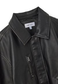 Giubbotto di pelle nera con colletto a punta, tasca sul petto con zip e dettagli trapuntati lungo le cuciture per una maggiore texture.