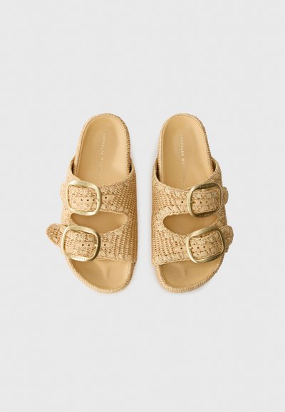 Sandales à glissière tissées beiges avec deux boucles réglables, une semelle plate et un design à bout ouvert en matériau texturé.