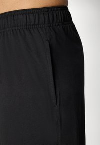 Black athletic shorts featuring an elastic waistband and side pockets, made from soft, lightweight fabric with a smooth texture.