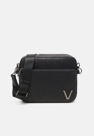 Sac bandoulière noir avec motif géométrique texturé, poche avant zippée, bandoulière réglable et logo métallique argenté en forme de V dans le coin inférieur avant.