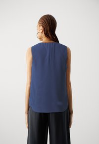 Top senza maniche blu navy in tessuto leggero con orlo posteriore arrotondato. Texture liscia, design minimalista e nessun motivo o accento visibile.