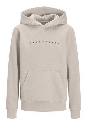 Αγόρι που φοράει μπεζ φούτερ Jack & Jones, μαύρο παντελόνι, μπεζ παπούτσια και μαύρο καπέλο, στέκεται μπροστά σε απλό ανοιχτό φόντο.