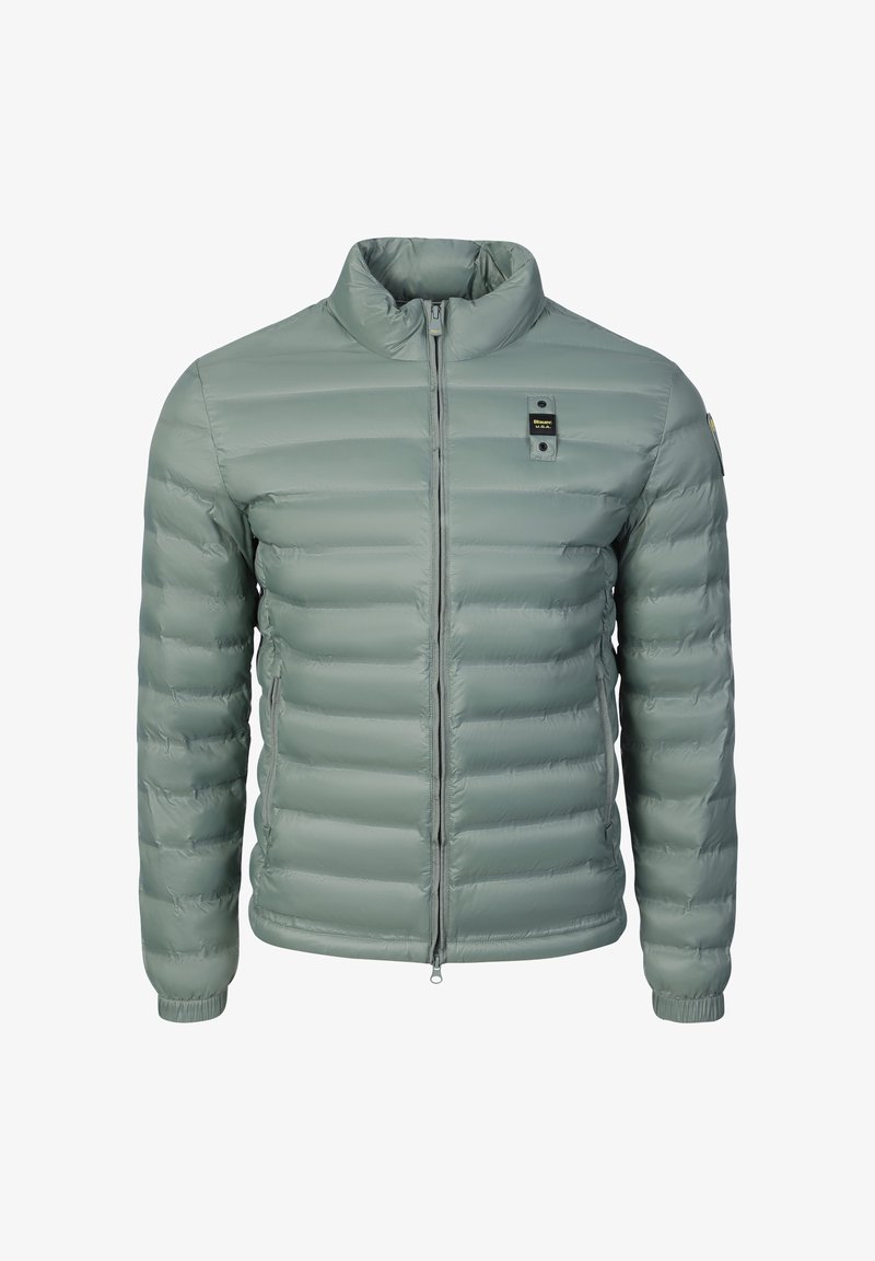 Veste matelassée vert clair avec col montant, fermeture éclair à l'avant, poignets élastiques, et petite étiquette noire sur la poitrine et la manche.