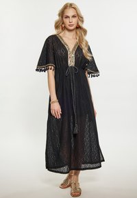 Rochie maxi din dantela neagra, cu maneci scurte, decolteu in V, decorata cu detalii colorate din mărgele si ciucuri. Are o talie ajustabila cu snur.