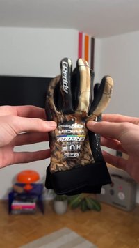 Luvas com padrão de camuflagem e detalhes em preto, apresentando áreas texturizadas para melhor aderência e ajuste justo para desempenho otimizado.