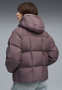 Puffjakke i dæmpet mauve med hætte, quiltet design og cropped pasform. Stoffet ser glat ud med en blød tekstur.