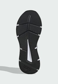 Semelle de chaussure en caoutchouc noir avec grip texturé, présentant un motif en chevron, des accents blancs et un logo au niveau du talon.