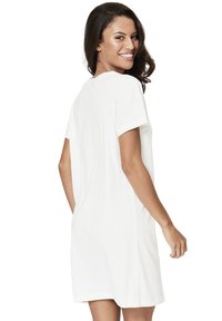 White short-sleeve dress with a loose fit and a round neckline. Smooth texture, mid-length, and subtle hem accents for a relaxed look.
