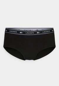 Fekete női alsónemű, puha, sima textúrával, fehér Lacoste logós pánttal a derékon és klasszikus, teljes takarást biztosító kialakítással.