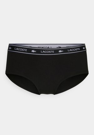 Zwarte damesonderbroek met een zachte, gladde textuur, voorzien van een witte Lacoste-logo band aan de taille en een klassieke full-coverage design.