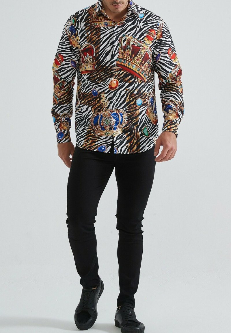 Chemise à manches longues présentant un motif zèbre audacieux, orné de couronnes dorées et de bijoux colorés. Fabriquée en tissu doux, avec une coupe structurée et un col.