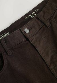 Chinos marroni scuri dalla vestibilità regolare con una texture liscia, passanti per cintura e chiusura con bottone metallico. Etichetta della taglia visibile: 34 R.