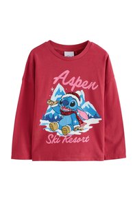 Maglietta rossa a maniche lunghe con una grafica di un personaggio in una scena invernale, con il testo "Aspen Ski Resort" in rosa e un accento luccicante.